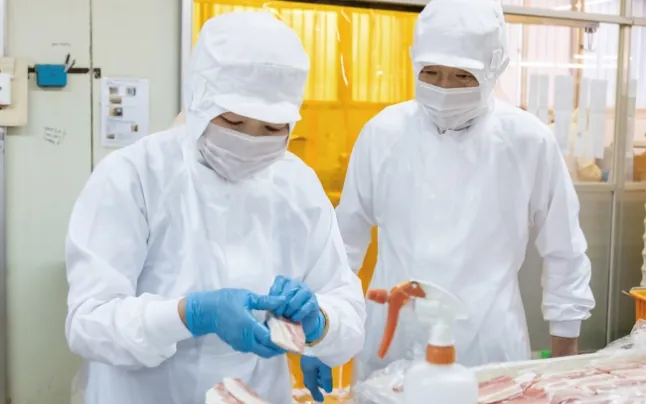 作業服姿で精肉作業に取り組む従業員